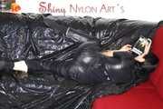 Lucy wearing a supersexy black rain catsuit posing and lolling on a sofa (Pics)