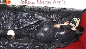 Lucy wearing a supersexy black rain catsuit posing and lolling on a sofa (Pics)