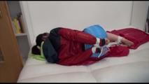 Jill tied and gagged on a white sofa wearing a lightblue nylon shorts and a red/darkblue rain jacket (Video)