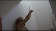 Mara tied and gagged over her head with cuffs on a stairway wearing a sexy black shiny nylon shorts and a golden rain jacket (Video)