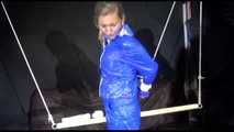 SUPERSEXY SANDRA wearing sexy shiny blue rainwear being tied and gagged overhead with ropes and a bar treated with a massager (Video)