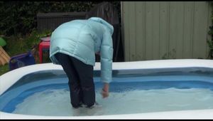 Watching sexy Mara wearing a blue rain pants and a lightblue down coat playing with water in the pool (Video)