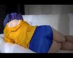 SEXY Mara wearing a blue shiny nylon shorts and a yellow rain jacket reading and lolling on the sofa (Video)