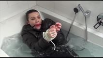 Jill tied and gagged in a bath tub wearing shiny nylon rain pants and a shiny down jacket (Video)