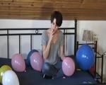 Smoking teen plays with many balloons