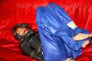 Sonja wearing a sexy blue shiny nylon raver pants and a black down jacket being tied and gagged with ropes on a sofa (Pics)