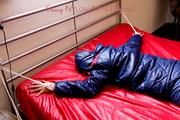 Pia hooded, tied and gagged on bed in a dark blue old school down ski suit