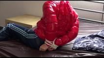 Mara tied, gagged and hooded on bed wearing s shiny red down jacket and a darkblue rain pants (Video)