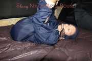 Sexy Sandra wearing a sexy shiny nylon rainwear combination being tied hand to feet and gagged with a cloth gag on a sofa (Pics)