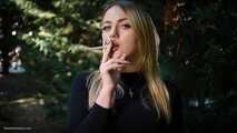 Blond lady is smoking white cigarette outdoors