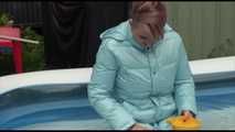 Watching sexy Mara wearing a blue rain pants and a lightblue down coat playing with water in the pool (Video)