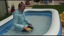 Watching sexy Mara wearing a blue rain pants and a lightblue down coat playing with water in the pool (Video)