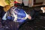 Pia tied, gagged and hooded on a bed wearing a sexy black shiny nylon pants and a blue/black down jacket (Pics)