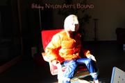 Pia tied and gagged on a chair wearing a shiny orange down jacket and a shiny blue rain pants (Pics)