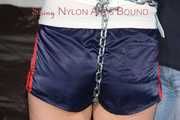 Sexy Pia tied and gagged overhead with chains, cuffs and a holster with a ballgag wearing shiny nylon shorts and a top (Pics)