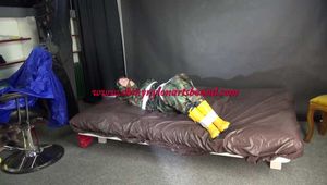 Watching sexy Pia being tied and gagged with tape on a bed wearing a sexy camouflage shiny nylon rainpants and a rainjacket as well as yellow rubber boots (Video)