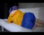 SEXY Mara wearing a blue shiny nylon shorts and a yellow rain jacket reading and lolling on the sofa (Video)