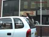 029013 Robyn Pees Behind A Parked Car In The Busy Shopping Street