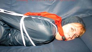 Leonie tied, gagged and hooded sitting on a sofa wearing a sexy shiny nylon shorts and a rain jacket (Pics)