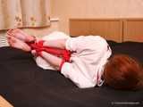 Barefoot nurse Gatitta tied up with a red rope