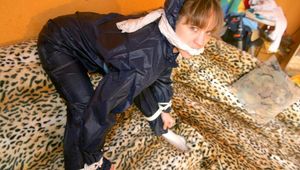 Leoni tied and gagged on a sofa wearing a sexy shiny nylon pants and a rain jacket (Pics)