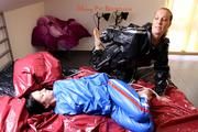 Simone tied and gagged by Sophie in bed wearing a blue and black shiny PVC sauna suit (Pics)