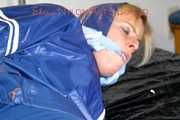 Pie tied and gagged with a bar on a bed wearing sexy blue shiny nylon AGU rainwear combination (Pics)