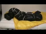 Jill in a blue shiny down jacket and black shiny rainwear tied and gagged in a shiny red/black big shiny nylon bag to lie in (Video)