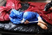 Simone tied and gagged by Sophie in bed wearing a blue and black shiny PVC sauna suit (Pics)