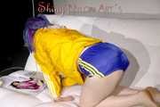 SEXY MARA lounging on the sofa wearing a sexy blue/yellow shiny nylon shorts and a yellow shiny nylon rain jacket (Pics)