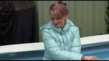 Watching sexy Mara wearing a blue rain pants and a lightblue down coat playing with water in the pool (Video)