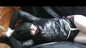 0345 min video with Jill in a black shiny nylon short with red stripes and a black shiny rain jacket bound, gagged and hodded on bed