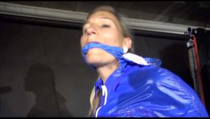 SUPERSEXY SANDRA wearing sexy shiny blue rainwear being tied and gagged overhead with ropes and a bar treated with a massager (Video)