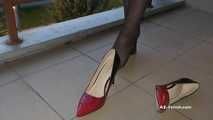Dipping classic red high heels on balcony