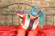 Mara tied, gagged and hooded on bed wearing a shiny red/blue/white striped old school down jacket and a skibib in red (Pics)