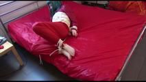 Mara tied, gagged and hooded on bed wearing a shiny red old school down jacket and pants (Video)