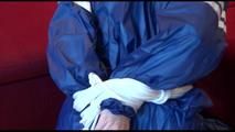 Mara tied and gagged on a sofa wearing a shiny blue PVC sauna suit (Video)