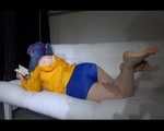 SEXY Mara wearing a blue shiny nylon shorts and a yellow rain jacket reading and lolling on the sofa (Video)