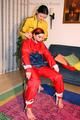 Jill tied by her friend in shiny yellow and red rainsuits
