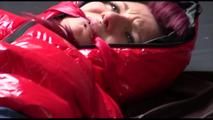 Mara tied, gagged and hooded on bed wearing s shiny red down jacket and a darkblue rain pants (Video)