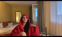 Miss Amira in a red minidress and red nylon raincoat having fun in a hotel room