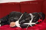 Lucy wearing a black shiny nylon rainh pants and a black down jacket tied and gagged on a sofa (Pics)