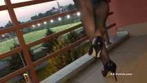 Dipping classic red high heels on balcony