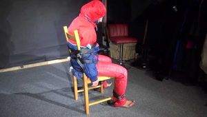 Sandra wearing a sexy OLDSCHOOL shiny nylon downsuit sitting on a chair being tied, gagged and hooded with tension belts and a clothgag (Video)