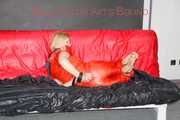 Pia tied and gagged with nack ties on a bed wearing a sexy red shiny nylon rainwear catsuit (Pics)