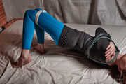 Tied arms and suspended legs in blue leggings