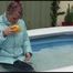 Watching sexy Mara wearing a blue rain pants and a lightblue down coat playing with water in the pool (Video)