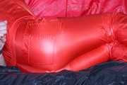 Pia tied and gagged with nack ties on a bed wearing a sexy red shiny nylon rainwear catsuit (Pics)