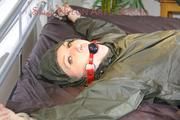 Mara wearing supersexy green rainwear tied on bed with cuffs and gagged with a ball gag (Pics)