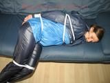 Katharina tied, gagged and hooded (breath control) on a sofa wearing sexy blue shiny nylon rainwear (Pics)